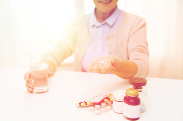 happy senior woman with water and pills at home