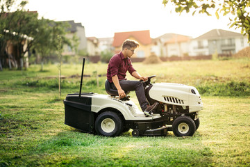 Gardner mowing lawn with ride-on tractor