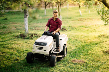 Man using ride on lawnmower, male riding lawn tractor and relaxing during sunset golden hour