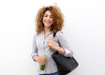 Happy young woman holding juice drink by white wall