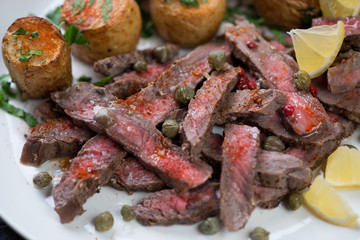 Close-up of beefsteak tagliata served with olive oil, capers, paprika and lemon, selective focus
