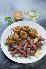 Tagliata beef steak served with baked potato on a white plate, studio shot