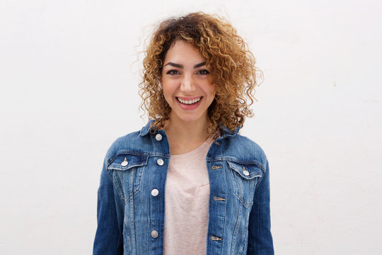 confident young woman with curly hair smiling abasing white background