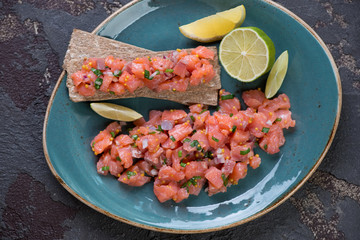 Close-up of a turquoise plate with salmon tartar, view from above, studio shot