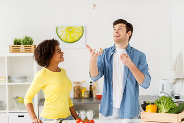 couple cooking food and juggling garlic at home