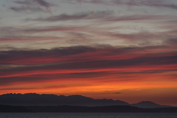 Fototapeta na wymiar Vibrant orange sunset over mountains and sea