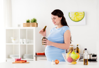 pregnant woman eating pickles at home kitchen