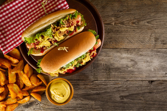 Variety of classic traditional american tasty junk unhealthy food on wooden background with copy space. Hot Dogs and Chips.