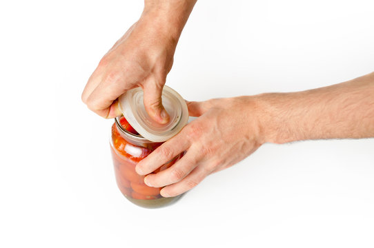 Masculine hands open the lid of glass jar with tomatoes