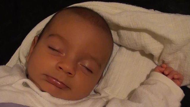 Baby tries to open his eyes waking up and winces