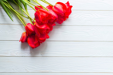 Fresh Red tulips flowers on white wooden background. Spring concept. Beautiful Card for Happy Mother's Day, Valentine's Day, Woman's Day 8 March. Top view, flat lay, copy space.