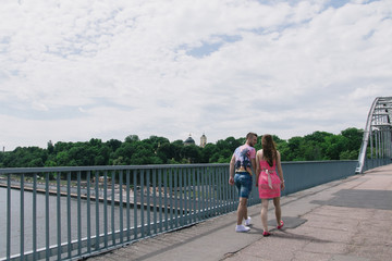Fototapeta na wymiar Young couple hugging and smiling each other walking on a bridge