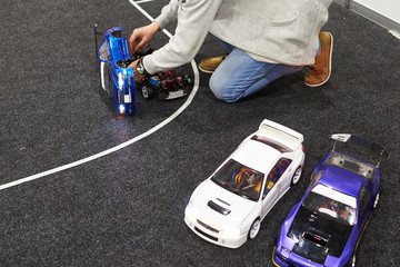 Man repairs radio-controlled car on race track