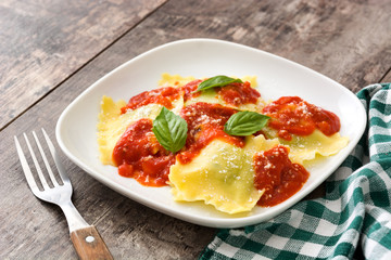 Ravioli with tomato sauce and basil on wooden background. 
