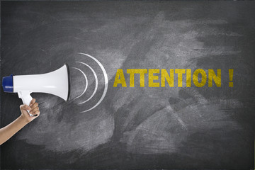 Megaphone with attention text on blackboard