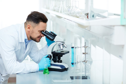 Portrait of smiling scientist using microscope in laboratory while working on important medical research