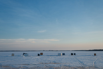 Ice fishing shacks out on the frozen harbour at dusk  in rural Prince Edward Island, Canada.