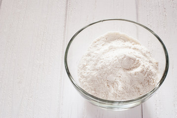 Flour in a transparent bowl on white boards