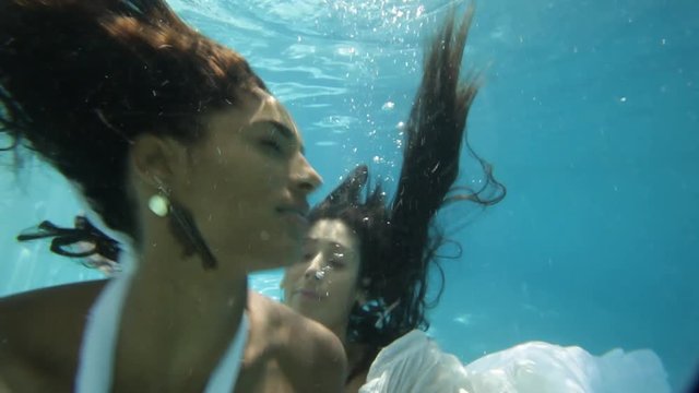 Two women sensually embrace, underwater
