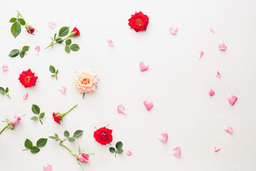 Flowers and petals background  made of pink and red roses, green leaves and pansy flowers on white background. Flat lay, top view