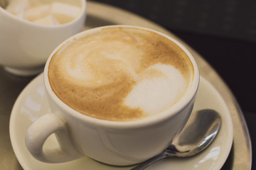 A cup of cappuccino with sugar in a modern cafe