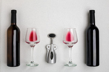 Glasses and bottles of red and white wine on white background from top view