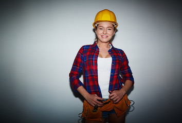 Confident young mechanic looking at camera with charming smile while standing against white background