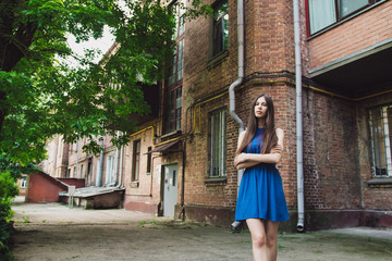 A very beautiful and cheerful girl stands on the street near a brick wall