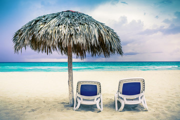 Two chaise lounges and an umbrella on the beach