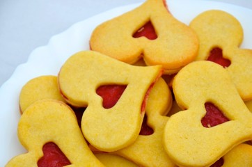 Traditional small Linz cakes in the shape of hearts. Filled by red berries jam. Detail photo of white plate. Valentine's, Christmas or wedding cookies.