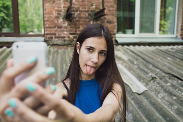 A very beautiful and cheerful girl stands on the street with long, luxurious hair and makes a selfie