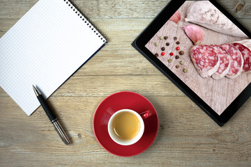 Blanko Einkaufszettel mit Kaffee und Tablet mit Salami