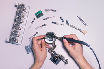 The engineer assembly the PCB (printed circuit board), soldering a microchip with tweezers and a...