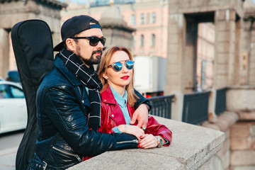 Beautiful couple in sunglasses on the bridge in city . Rock style .