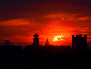 Dramatic red sunset with clouds and sun over big city
