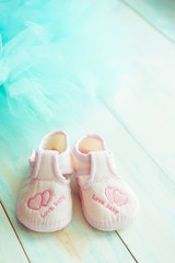 Pink booties for newborn baby on a wooden turquoise background