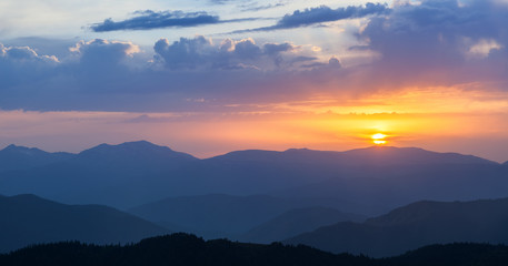 Mountain ridges at sunset against the sky with clouds