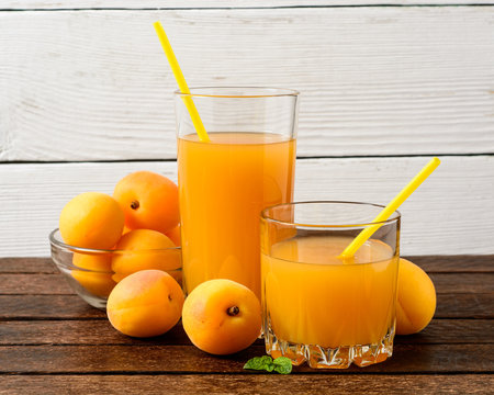 Fresh apricot juice and apricots on wooden table.
