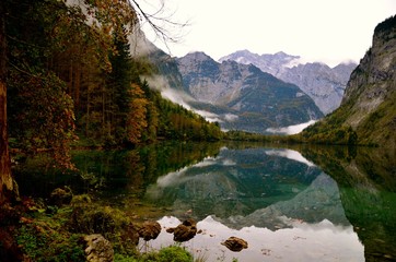 Autumn mountain's landscape with rocks, clouds and trees. Mirror reflection in the lake,