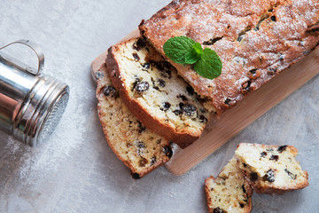 Traditional cake with raisins sprinkled with powdered sugar and mint leaves decorated. At Marble gray background