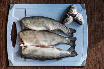 Three rainbow trouts on a cutting board with head cut off before cooking