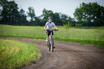 Smiling girl ride on bike on rural landscape