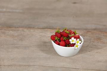 strawberries in a white bowl on a wooden table