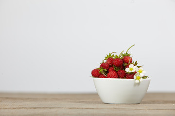 strawberries in a white bowl on a wooden table