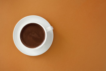 Coffee in white cup on brown background.