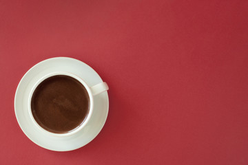 Coffee in white cup on red background.