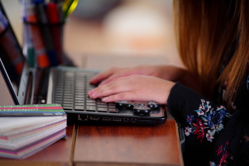 Young woman working in the computer and a popular fidget spinner toy over the laptop, on office background