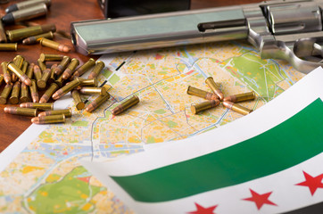 Close up of a shotgun and a revolver, cartridge belt with bullets with a blurred Iraq flag on a map, on wooden table