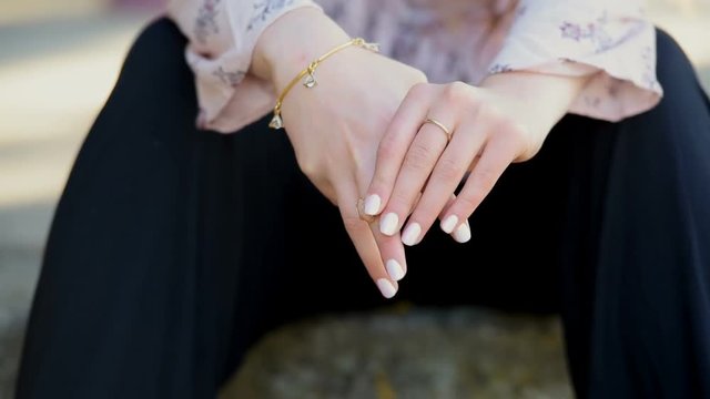 Young woman sitting outdoor remove and drop the ring on her finger 