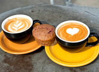Art milk mocha coffee with foam and muffin on metal table